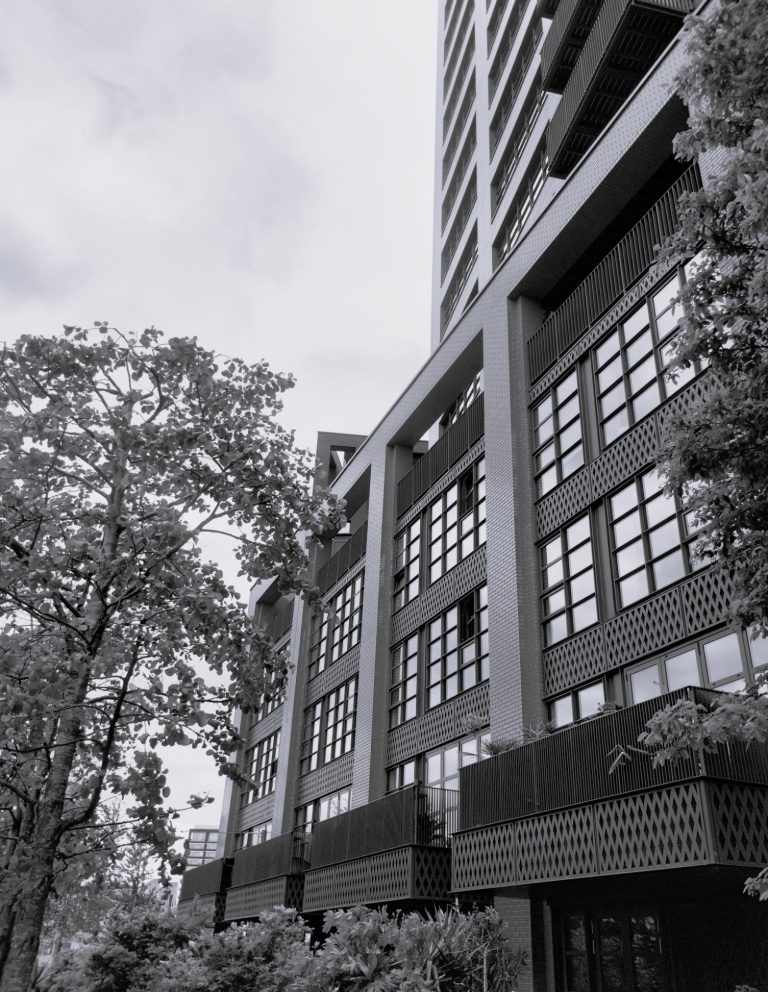 Four storey podium block formed of apartments, with tower of apartments above; landscaping in foreground